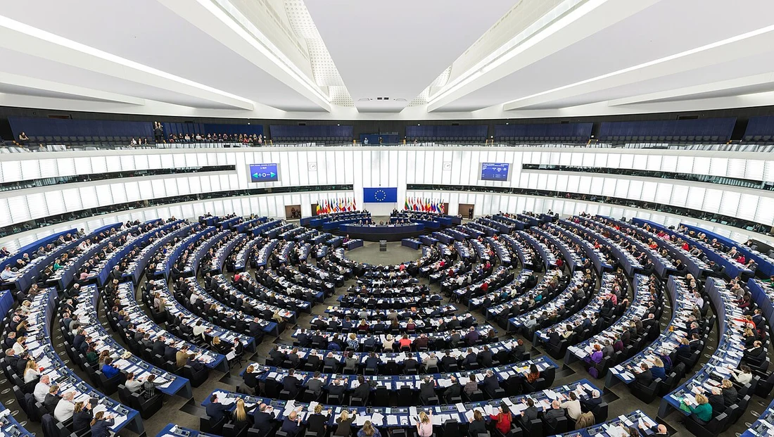 A full European Parliament plenary chamber in Strasbourg, with interpreting booths around the upper level