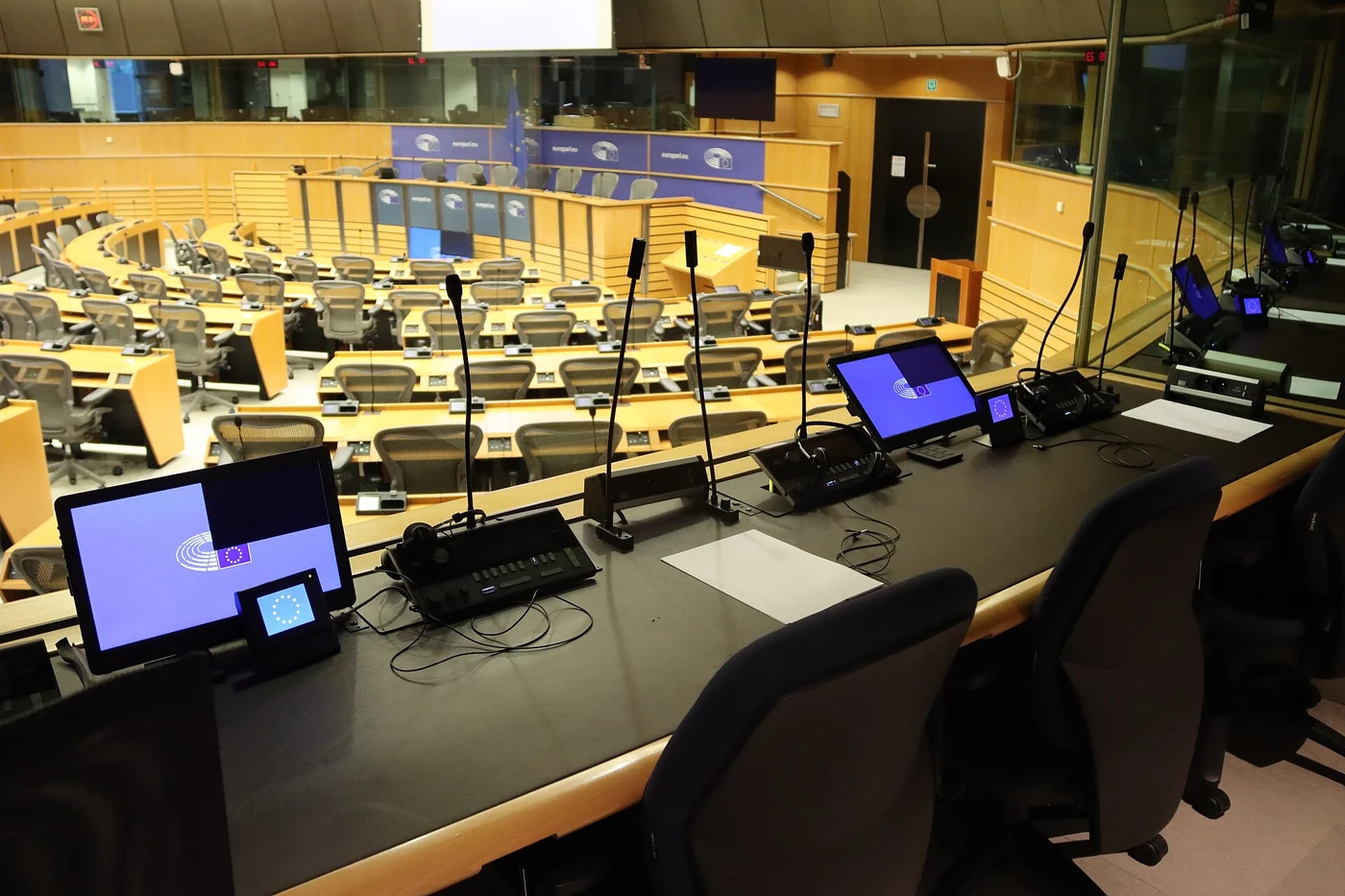 Interpreting consoles and microphones inside a European Parliament booth overlooking the conference room